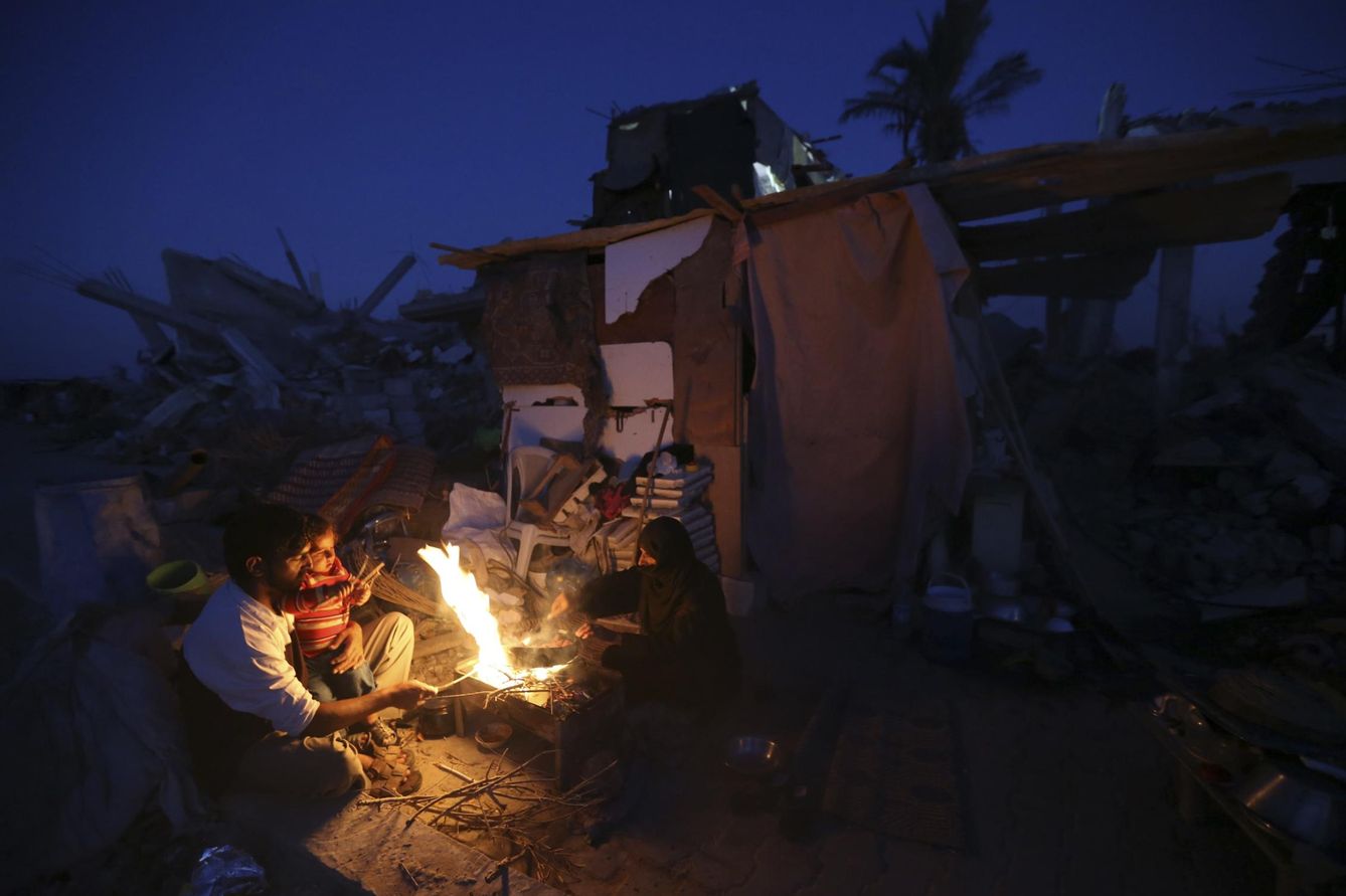 Palestinos cocinan en la puerta de su chabola ante los restos de su casa destruida en los bombardeos, en Khan Younis, Gaza (Reuters).