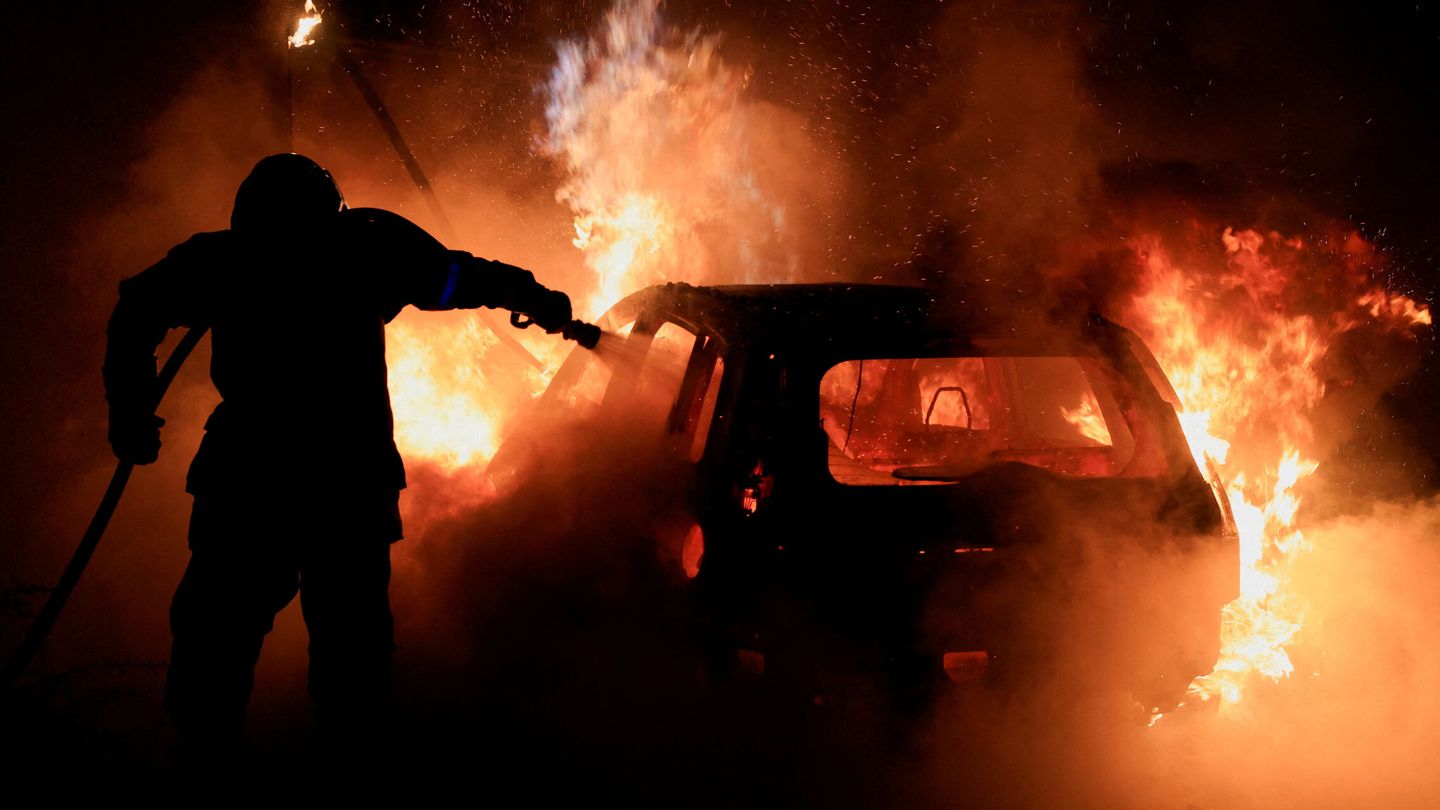 Bombero apagando un coche en llamas durante los disturbios de finales de junio tras el asesinato policial del joven Nahel Merzouk. (Reuters/Pascal Rossignol)