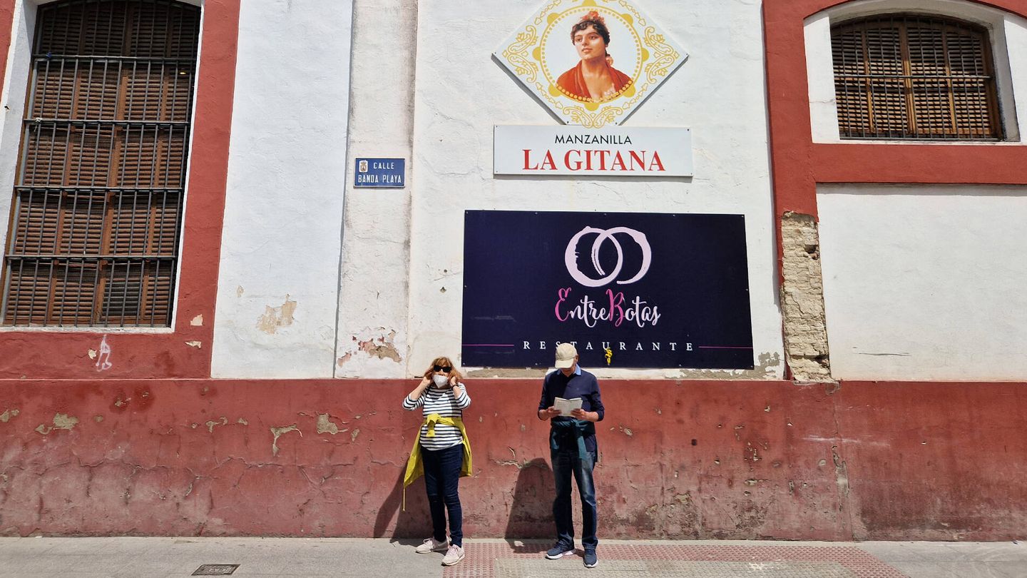 Dos turistas pasean por la calle Banda Playa, junto a la bodega de la manzanilla La Gitana, en el centro de Sanlúcar de Barrameda. (C. R.)
