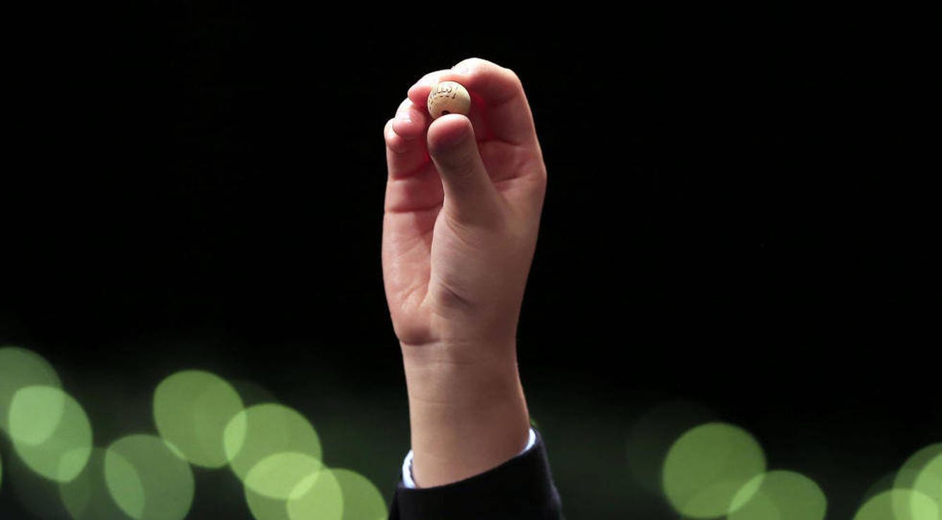 Un niño sostiene una de las bolas del sorteo (EFE)