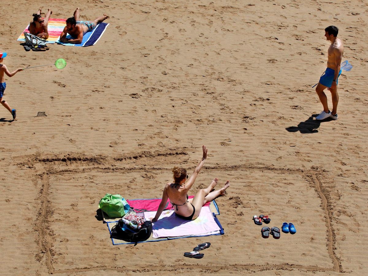 Foto: Varias personas disfrutan de un soleado día de verano en la playa de San Lorenzo en Gijón. (EFE)