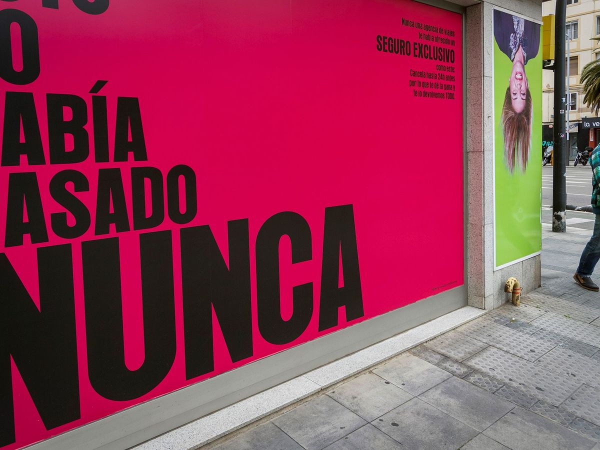 Foto: Un hombre protegido con una mascarilla pasa ante la fachada de una agencia de viajes en Zaragoza. (EFE)