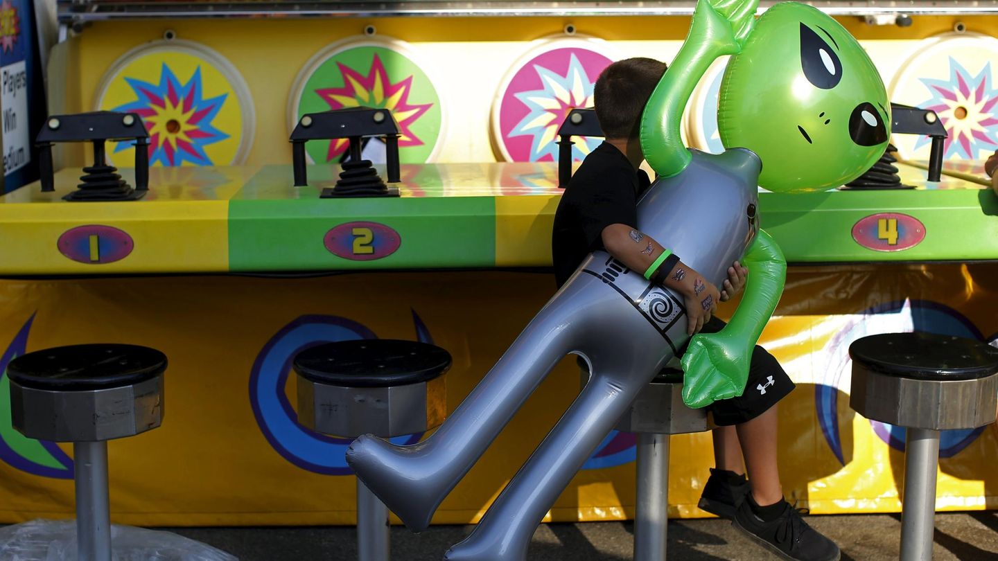 A boy carries an inflatable alien toy prize while sitting on a stool at the Iowa State Fair in Des Moines, Iowa, United States, August 15, 2015.  REUTERS/Jim Young