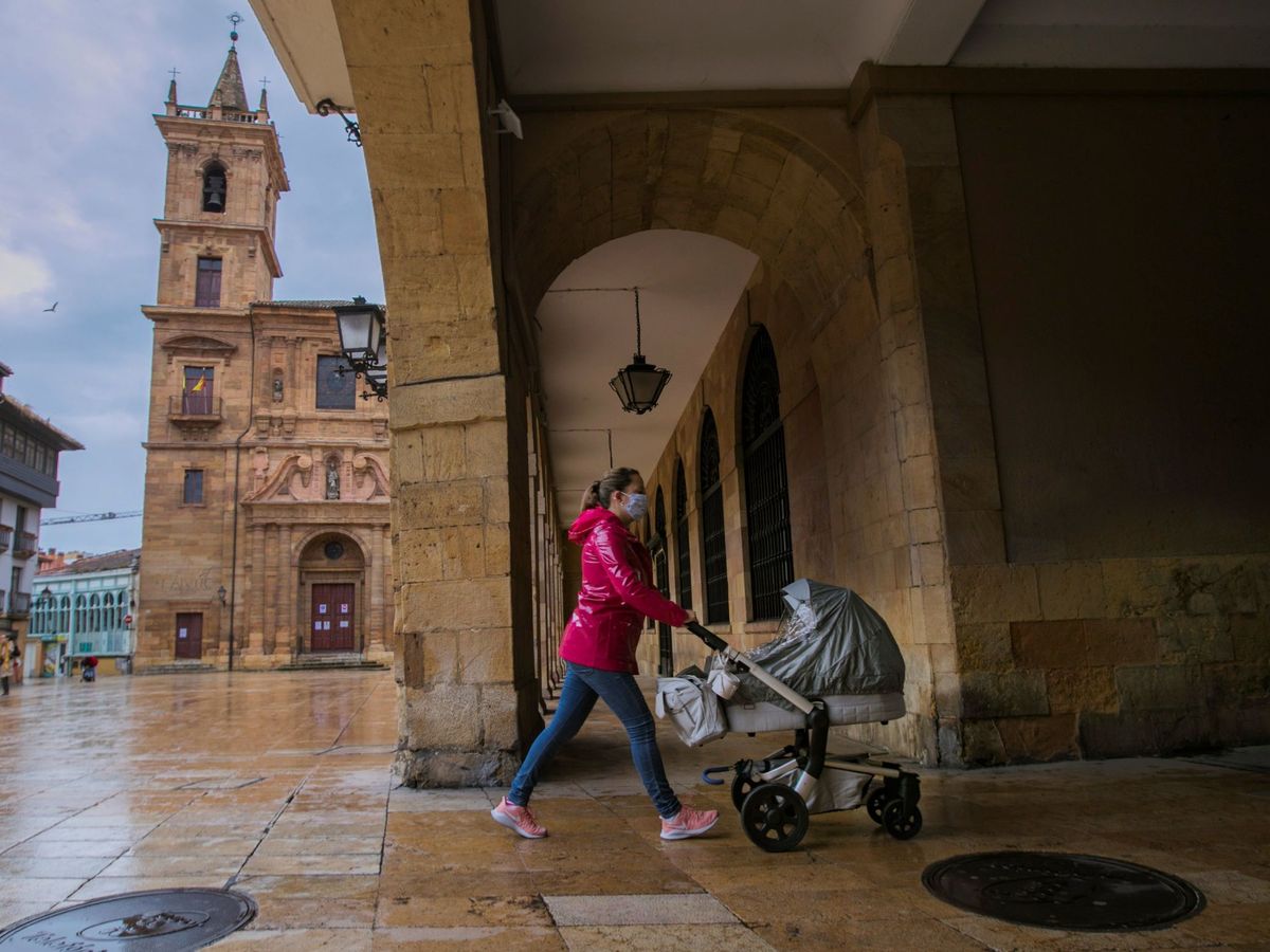 Foto: Un mujer pasea a su hijo por una calle de Oviedo. (EFE)
