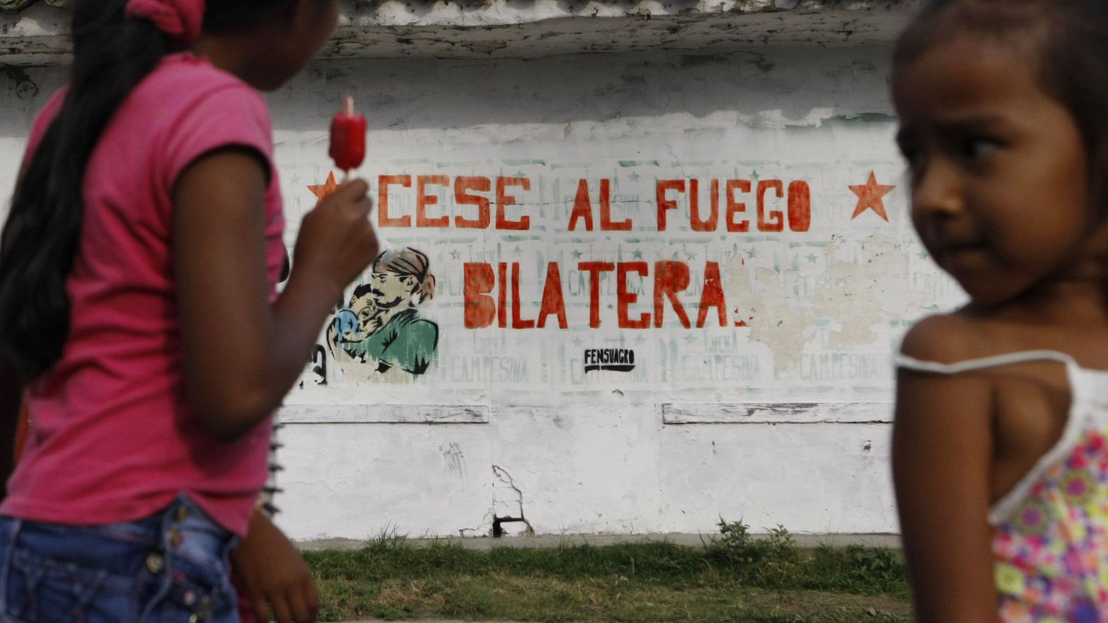 Foto: Dos niños en una de las calles de El Paulo, Cauca (Colombia), frente un mural alusivo al cese al fuego definitivo. (EFE)