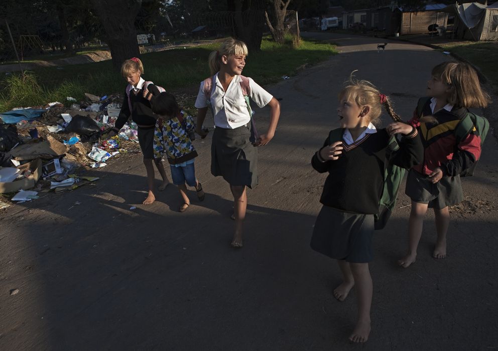 Foto: Niñas sudafricanas caminan descalzas hacia su escuela en un campamento para blancos pobres en Krugersdorp. (Reuters)