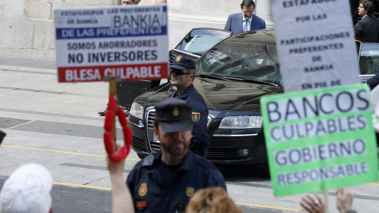 Foto: Protesta de los afectados por las preferentes con Rajoy al fondo. (EFE)