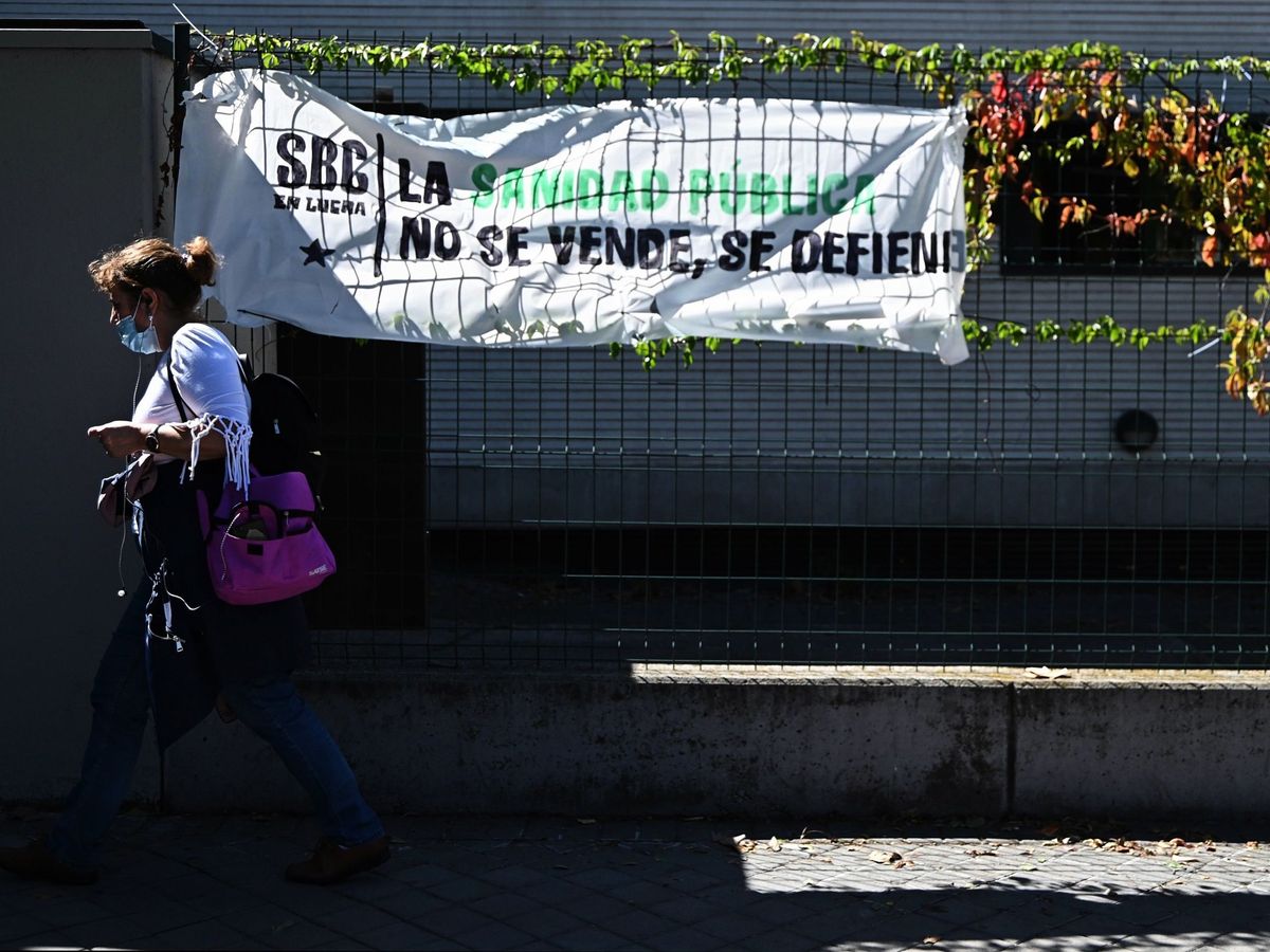 Foto: Una mujer pasa ante un cartel de defensa de la Sanidad pública en Madrid. (EFE)