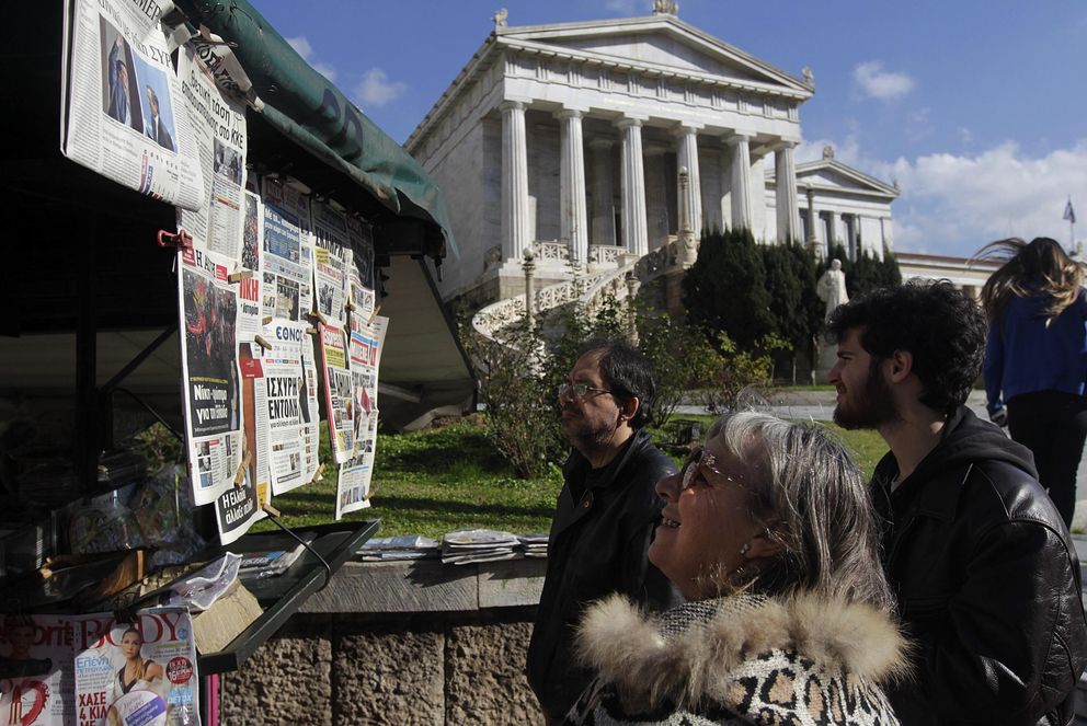 Varios griegos observan las portadas de los diarios tras la jornada electoral (Efe).