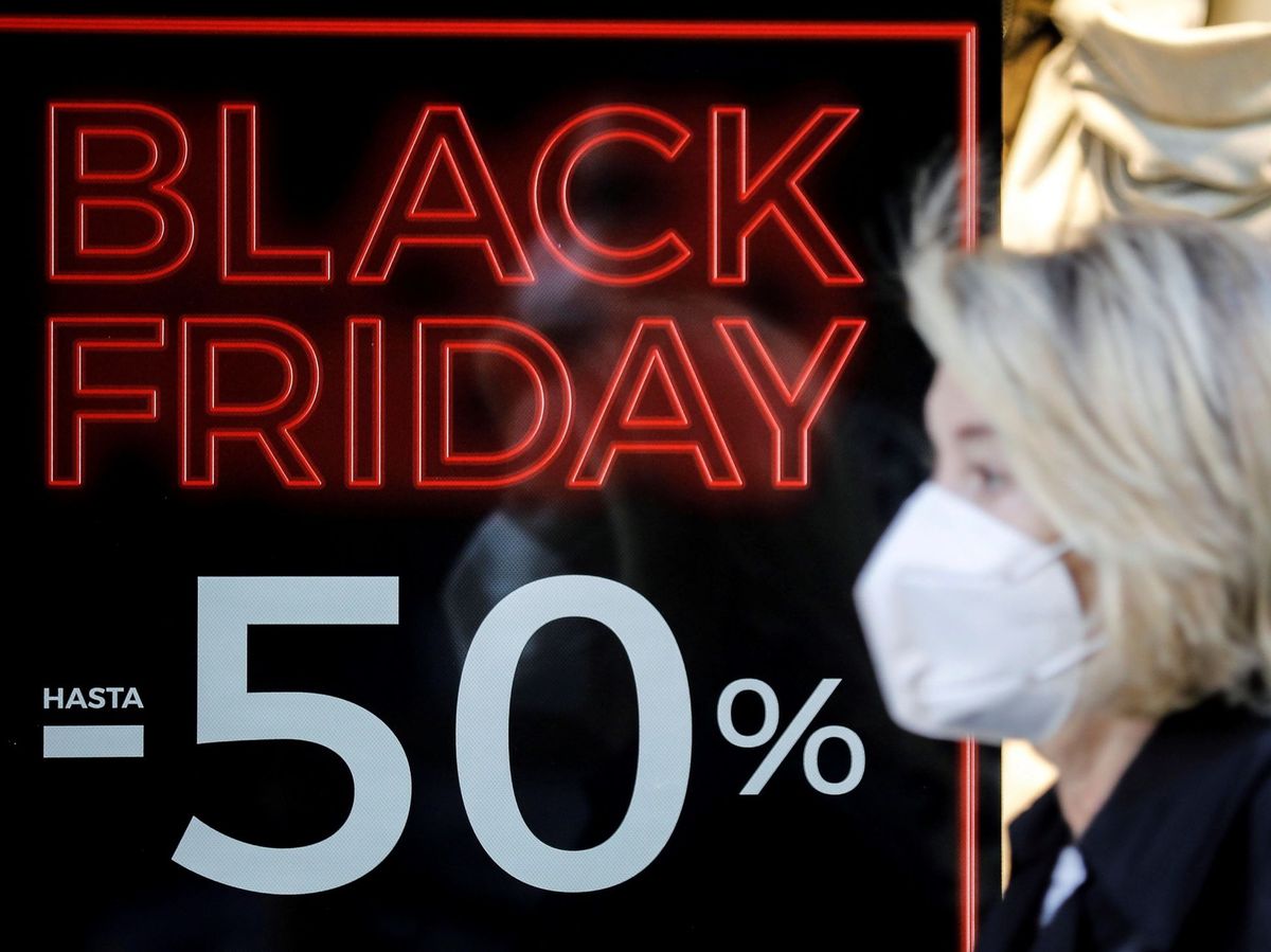 Foto: Una mujer con mascarilla pasea ante el escaparate de un comercio con promociones del Black Friday (EFE)