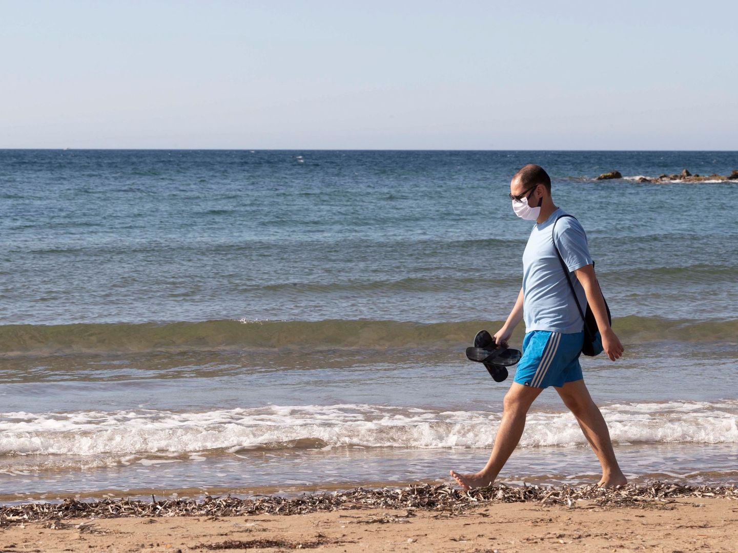 Un hombre con mascarilla camina este domingo por la playa de Rihuete, Mazarrón, Murcia. (EFE)