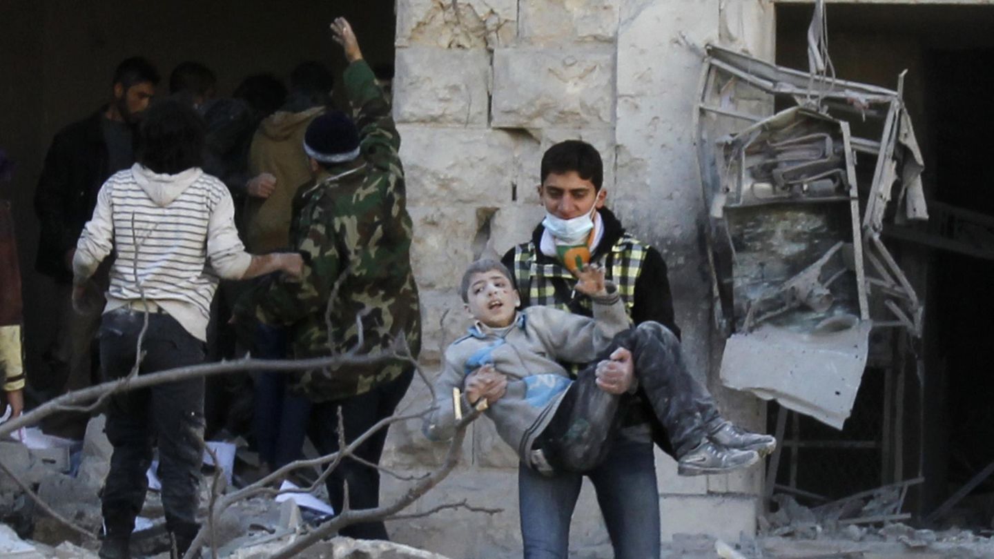 Un hombre traslada a un niño superviviente de un bombardeo en Alepo (Reuters).