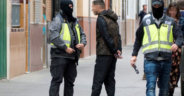 Foto: Dos agentes de la Policía Nacional caminan y hablan con algunas personas durante el registro de la casa en la que vivía el presunto yihadista. (EFE)