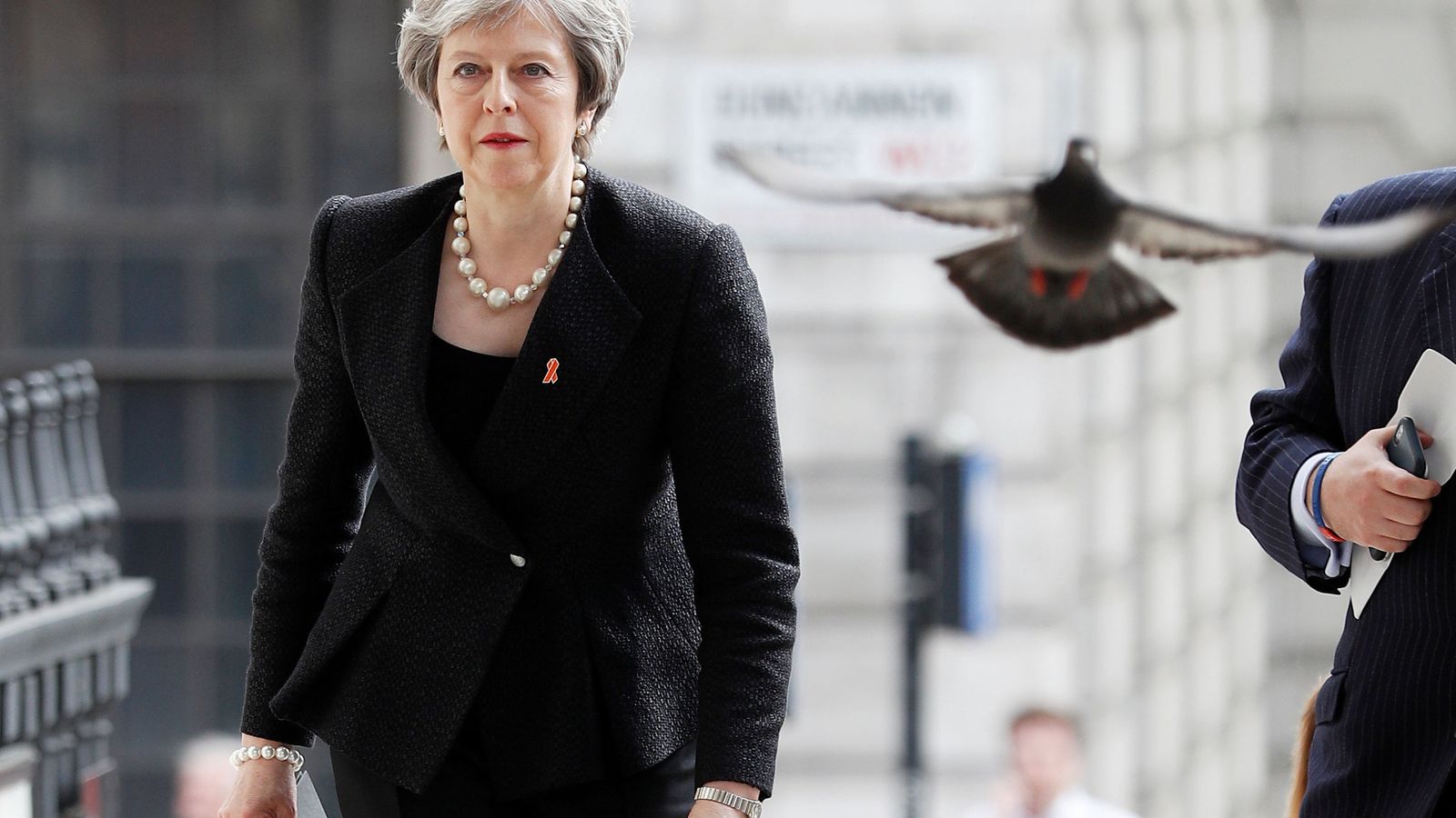 Foto: Una paloma alza el vuelo al paso de Theresa May durante un acto en Londres, el 23 de abril de 2018. (Reuters)