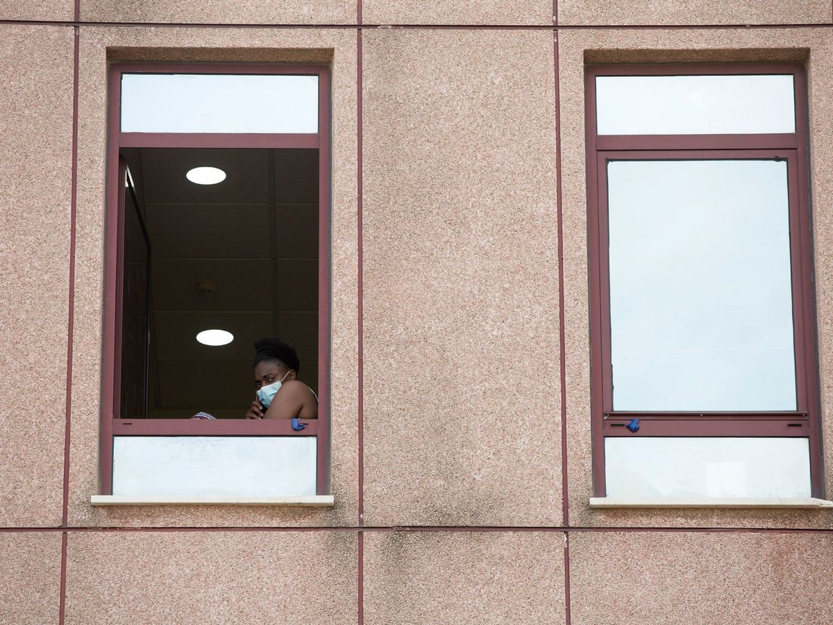Foto: Una persona habla por teléfono ante una ventana del Centro de Acogida, Emergencia y Derivación de Cruz Roja en Málaga. (EFE)