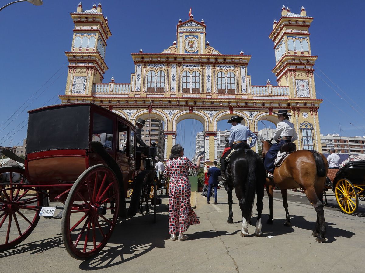 Foto: Coches de caballos frente a la portada de la Feria de Abril de Sevilla. (EFE/José Manuel Vidal)