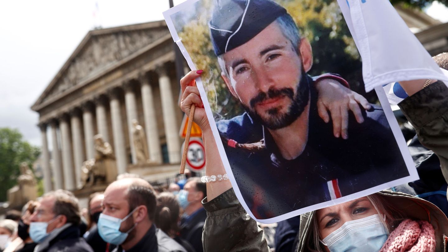 Una mujer sujeta una imagen del policía Eric Masson, asesinado durante una operación antidroga, durante la manifestación ante la Asamblea Nacional francesa en apoyo a las fuerzas de seguridad en mayo de 2021. REUTERS / Christian Hartmann
