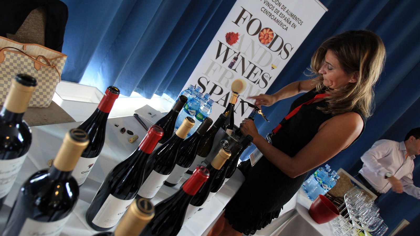 Foto: Una mujer expositora descorcha vinos españoles durante la II Exposición de Alimentos y Vinos de España en Centroamérica. (EFE)