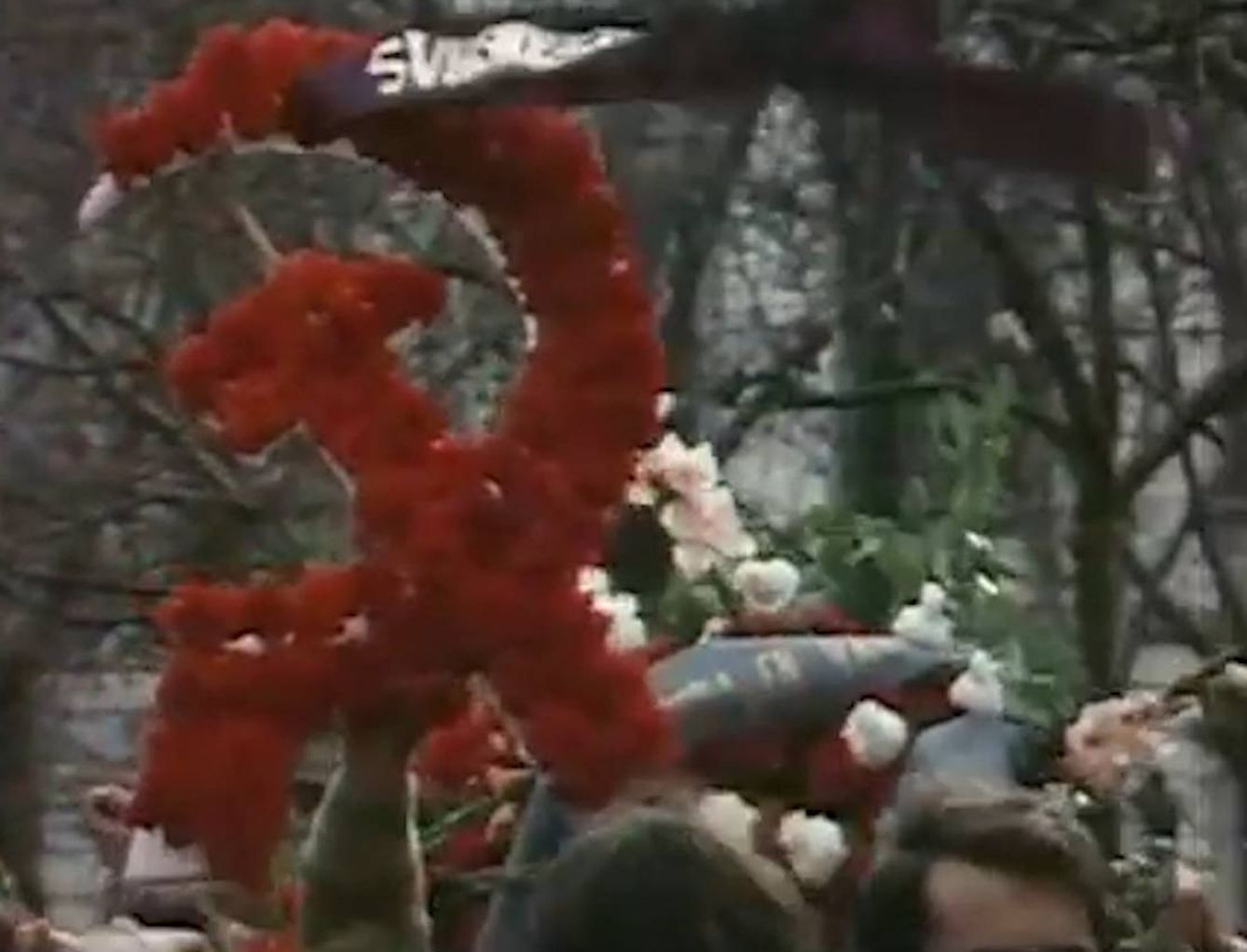 Corona de flores con el símbolo comunista de la hoz y el martillo.