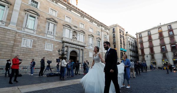 Foto: Una pareja de recién casados pasa por delante del Palau de la Generalitat. (Reuters)