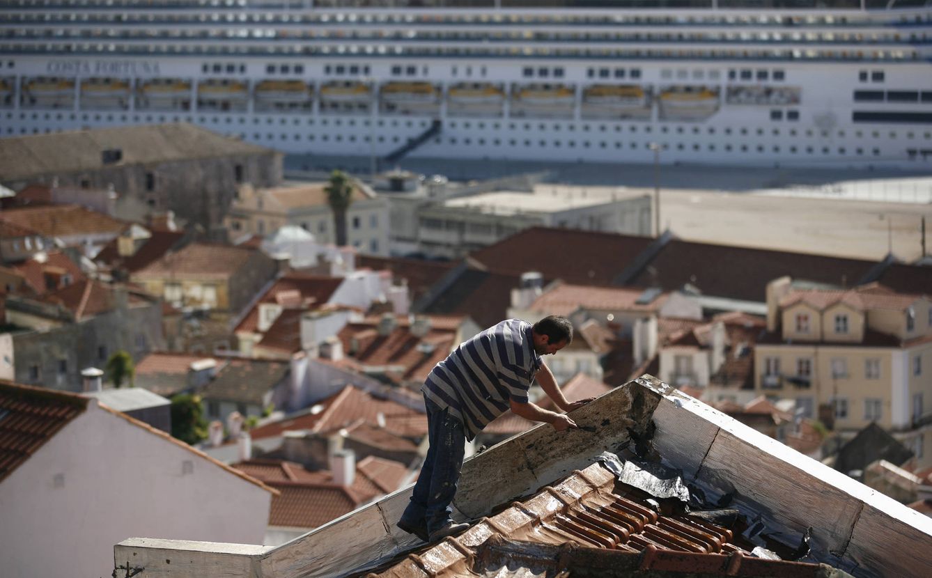 Un hombre repara el tejado de una casa en el barrio de Alfama, en Lisboa. (Reuters)
