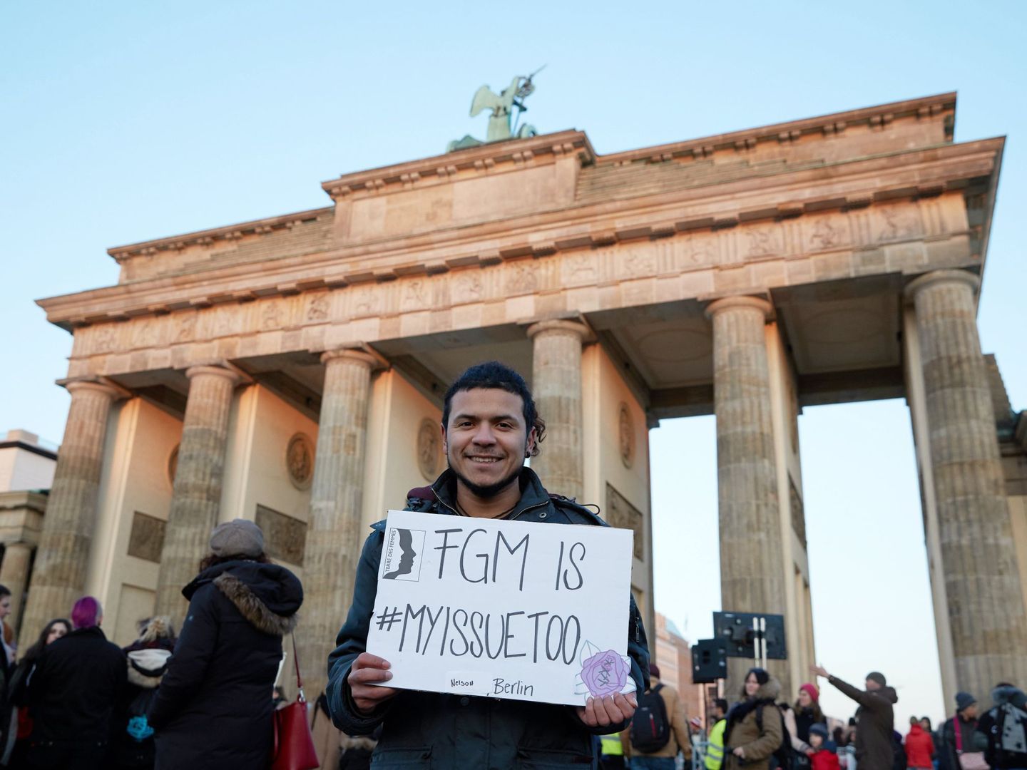 Un hombre posa con un cartel con el mensaje 'La mutilación genital femenina (FGM por sus siglas en inglés) es también asunto mío' mientras participa en una manifestación celebrada ante la Puerta de Brandemburgo. EFE