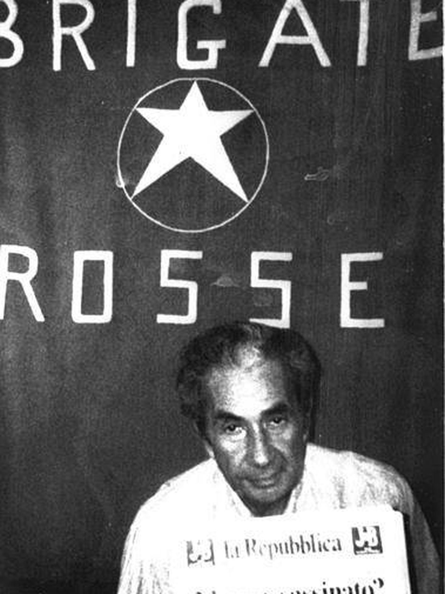 Aldo Moro en el lugar del secuestro junto a la bandera de las Brigadas Rojas.