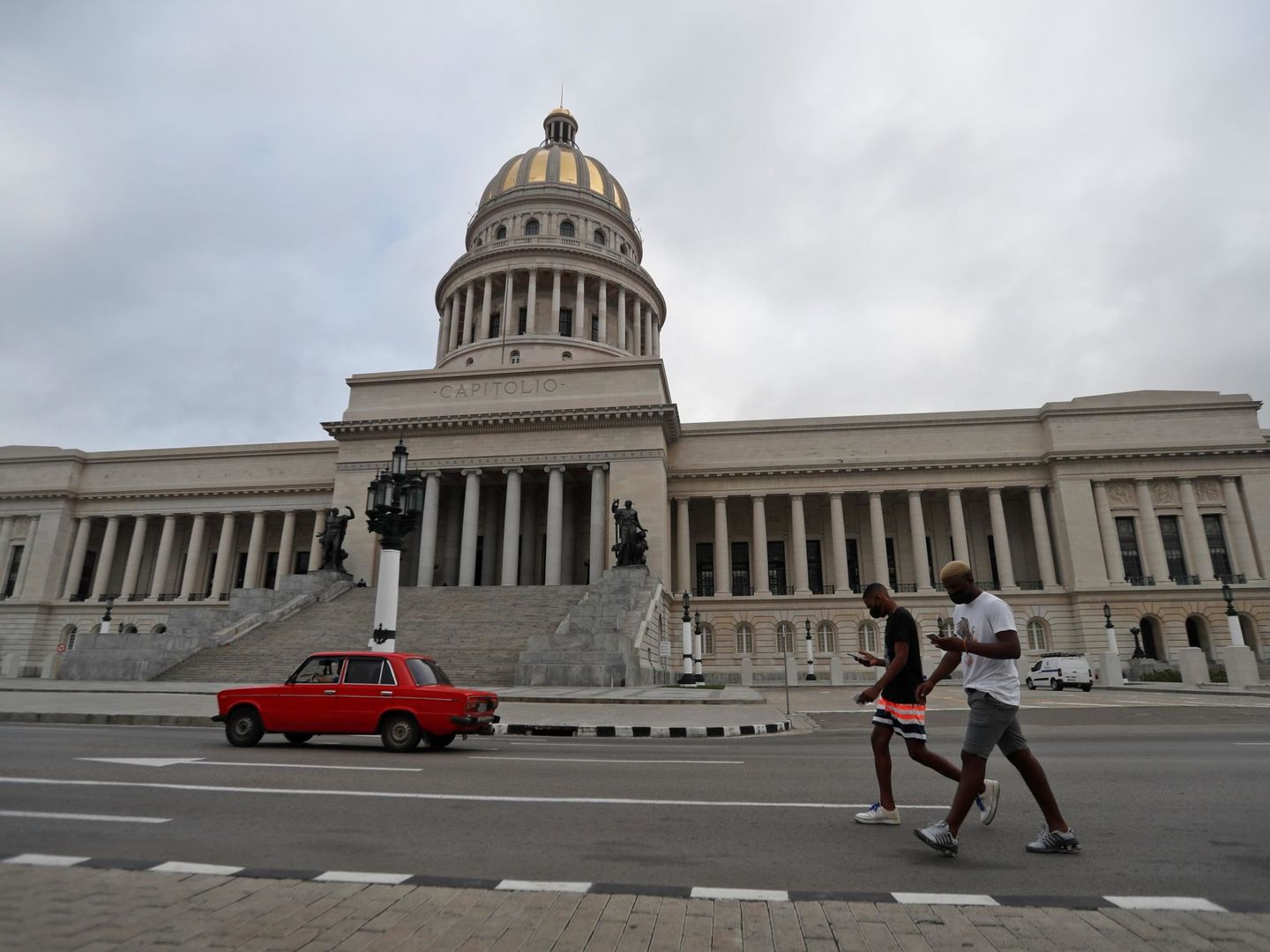 Dos personas caminan frente al Capitolio de La Habana.