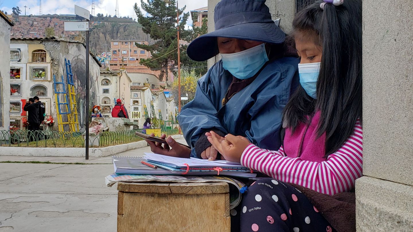 Trabajadora del cementerio de La Paz ayuda a su hija con la tarea. (Reuters)