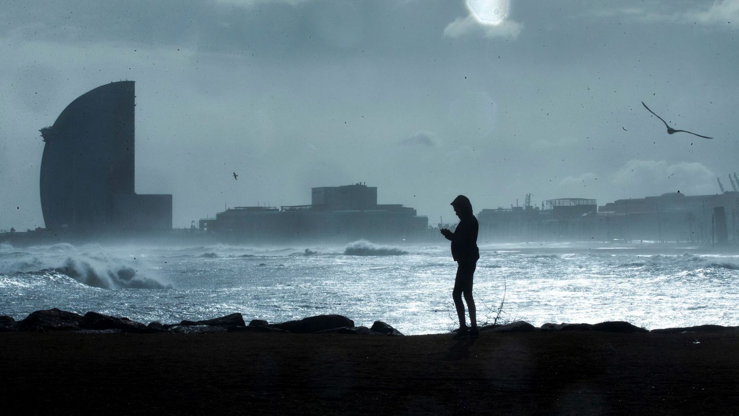 Una persona observa las grandes olas en la playa de la Barceloneta, en Barcelona. (EFE)