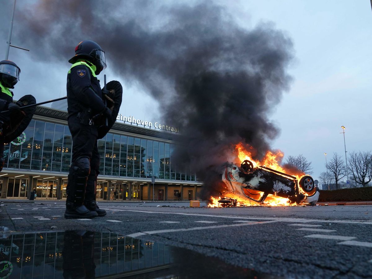 Foto: Un coche en llamas en Eindhoven, tras las protestas contra el confinamiento. (EFE)