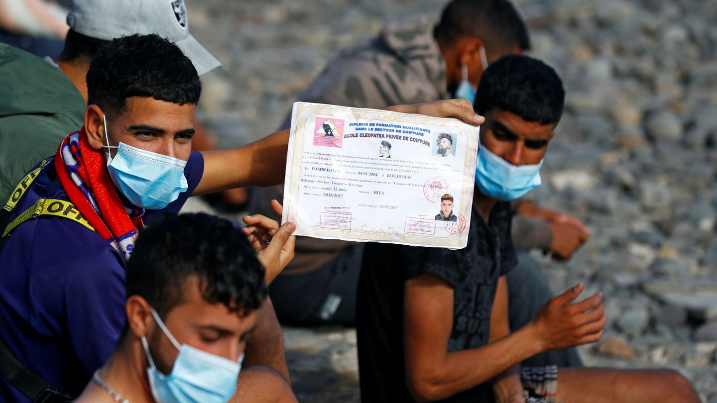 Un joven migrante muestra su certificado de estudios. (Reuters) 