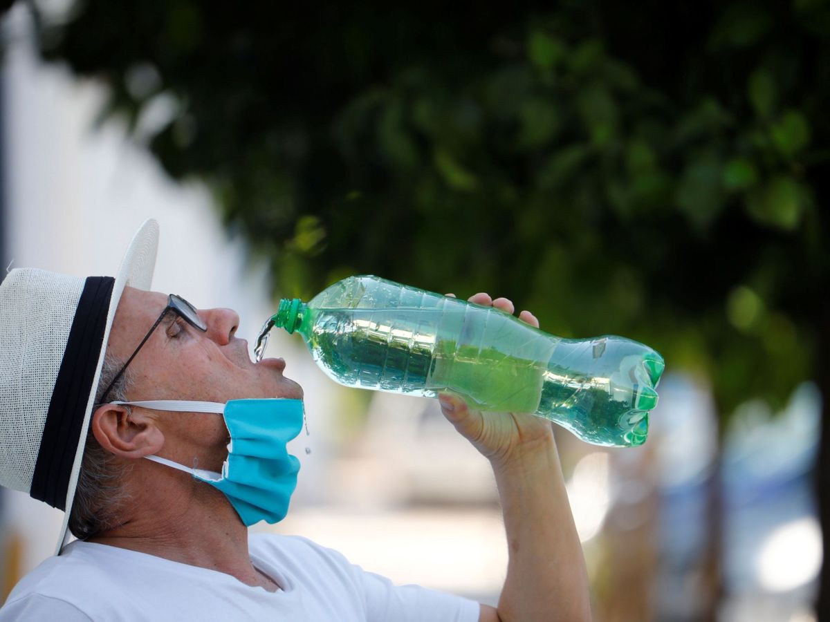 Foto: Un ciudadano se retira la mascarilla para beber. (EFE)