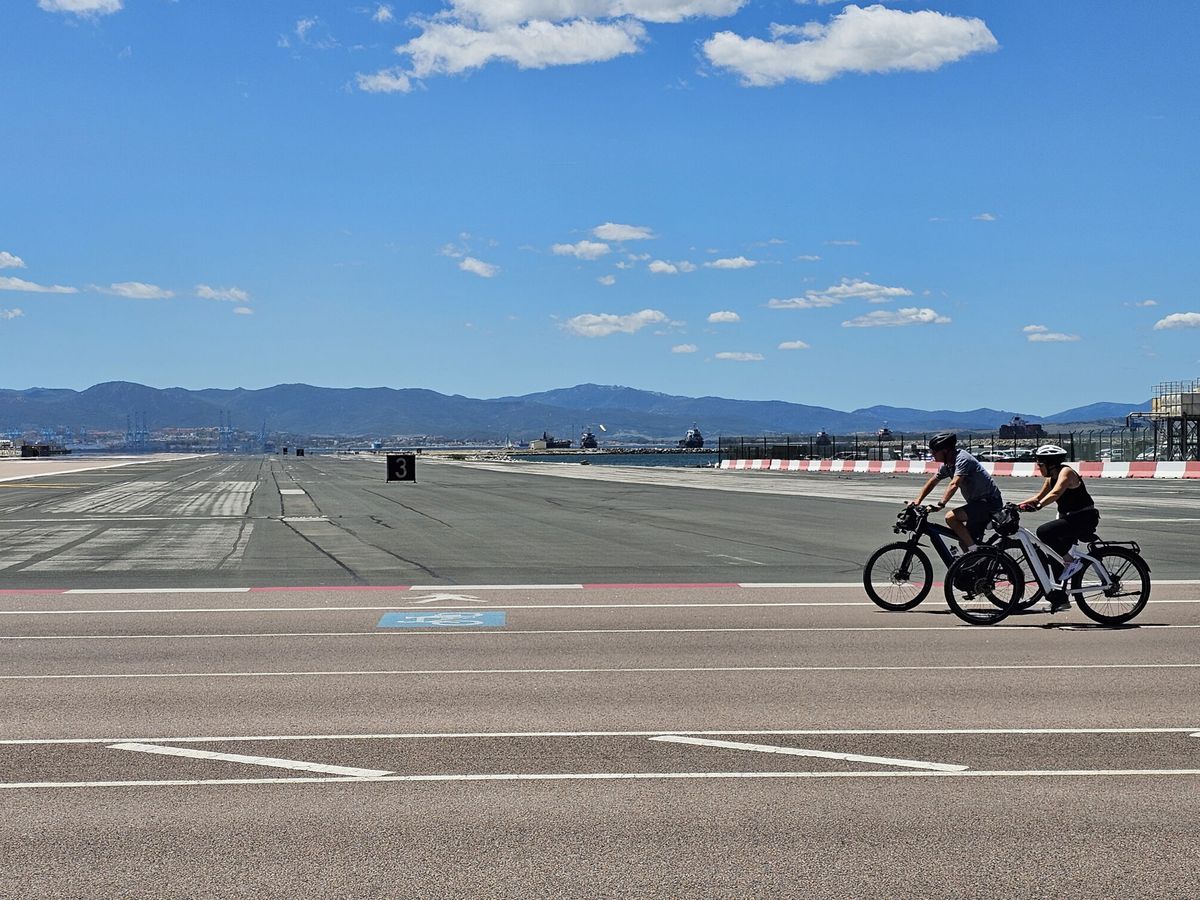 Foto: Dos ciclistas cruzan el aeropuerto de Gibraltar. (EFE/A. Carrasco)