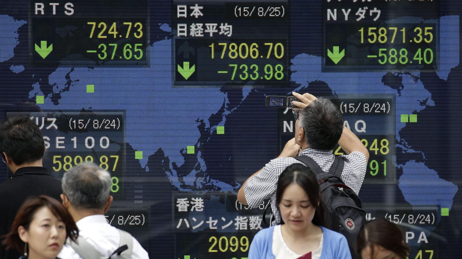Foto: Un hombre fotografía una pantalla que muestran información bursátil en la bolsa de Tokio. (EFE)