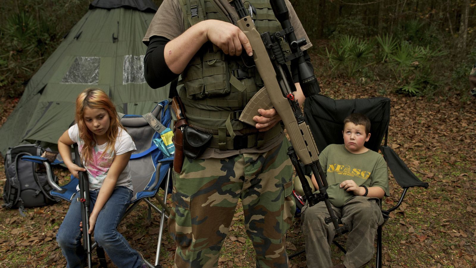Foto: Un miembro del Grupo de Supervivencia de Florida Norte espera con su rifle delante de sus hijos antes de un ejercicio paramilitar, en febrero de 2013. (Reuters)