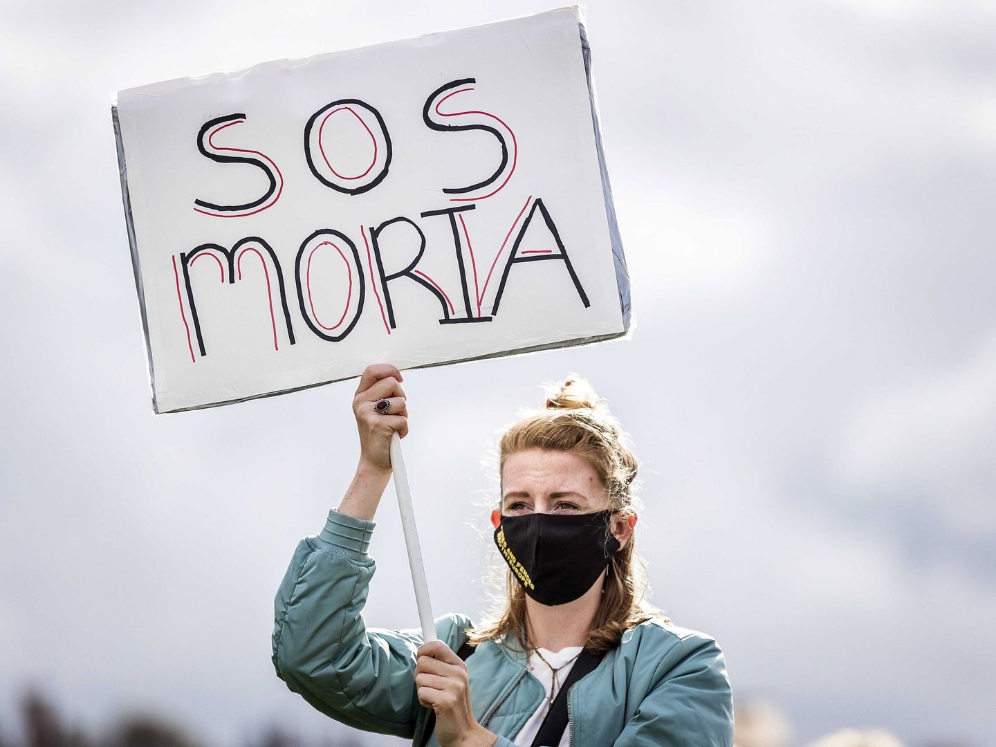 Una mujer sostiene un cartel en el que puede leerse 'SOS Moria' durante una manifestación para exigir el apoyo del Gobierno holandés al campo de refugiados griego de Moria, después de que una serie de incendios asolaran la zona, este sábado en Ámsterdam (Holanda). (EFE)