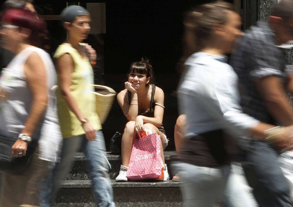 Foto: Una chica descansa con sus compras en una céntrica calle comercial en Barcelona (Efe)