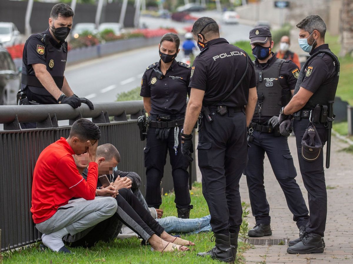 Foto: Efectivos de la Policía Nacional, junto a un grupo de migrantes, en Ceuta. (EFE) 