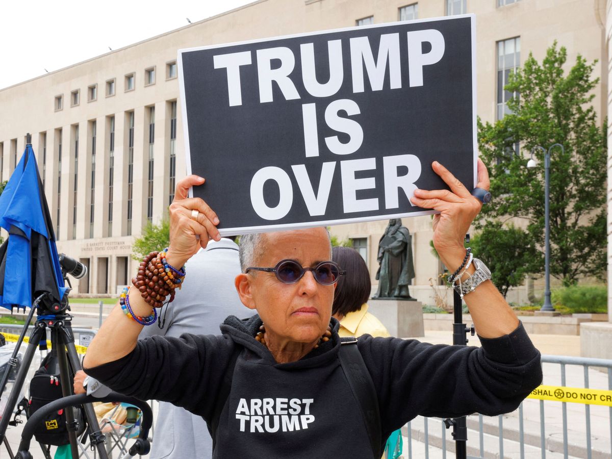 Foto: Un manifestante sostiene una pancarta ante la llegada del expresidente de EEUU Donald Trump al tribunal federal. (Reuters/Jim Bourg)