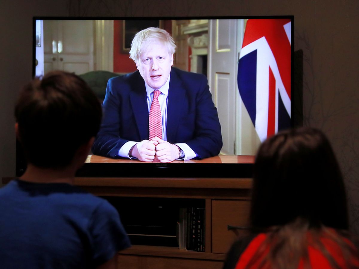 Foto: Dos niños observan el mensaje a la nación de Boris Johnson. (Reuters)