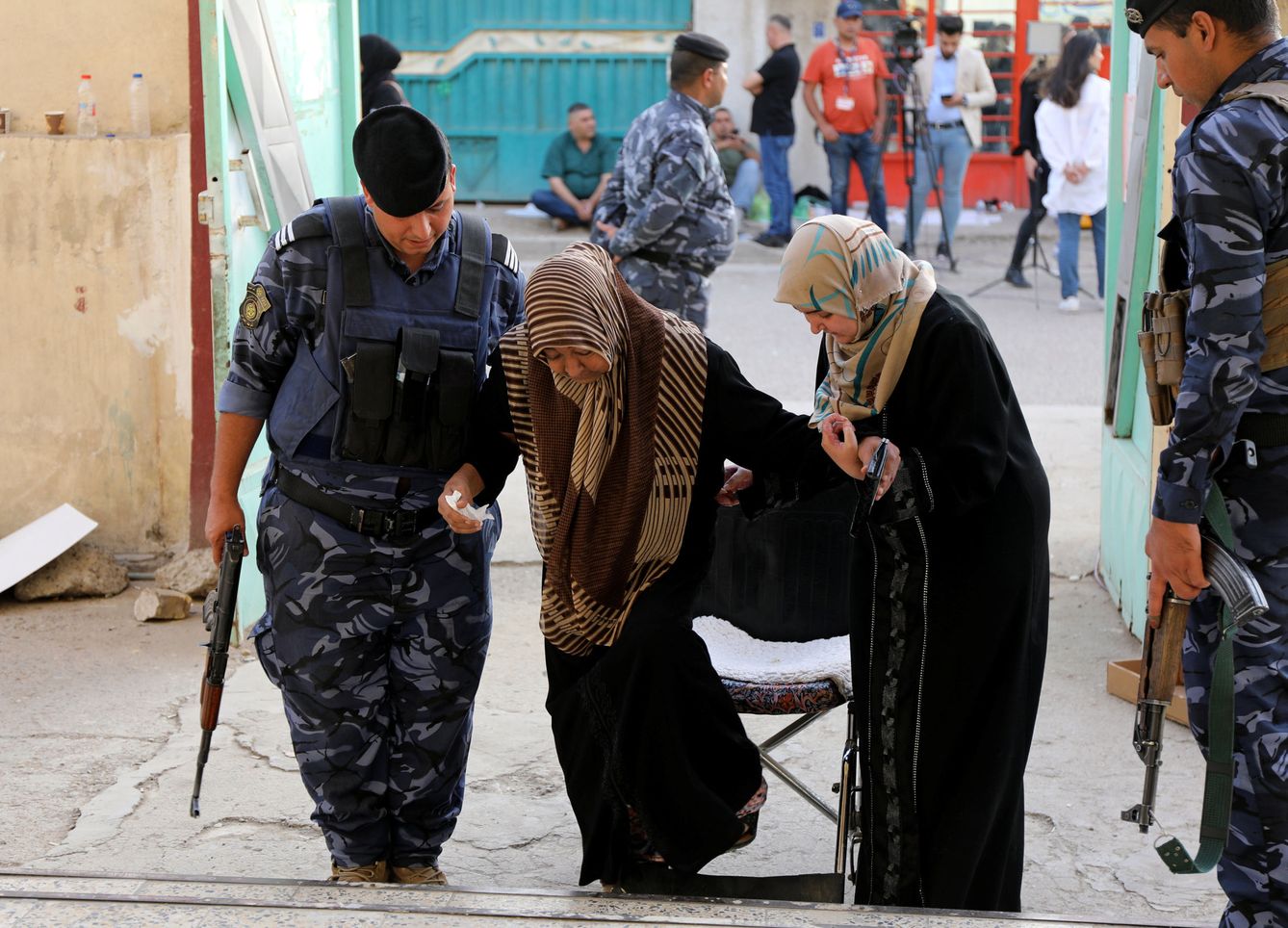 Un policía iraquí ayuda a una mujer a entrar en un centro de votación en Bagdad, el 12 de mayo de 2018. (Reuters)