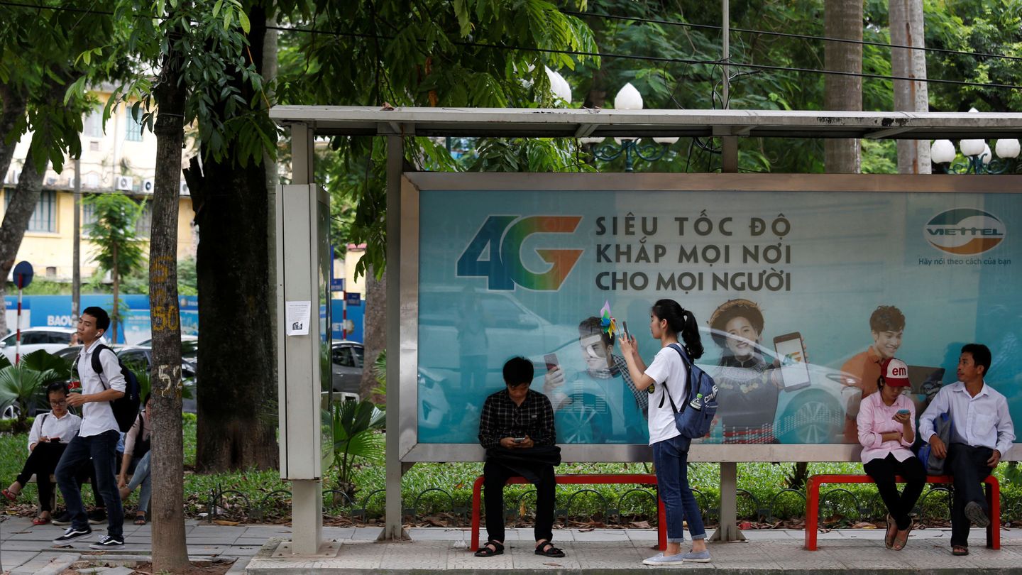 Usuarios de internet se conectan con sus móviles frente a un anuncio de conectividad 4G en una parada de autobús en Hanoi, en agosto de 2017. (Reuters)