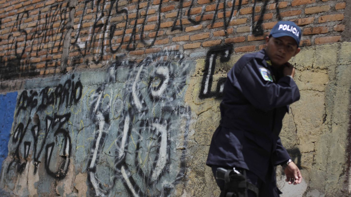 Un policía pasa por delante de un grafitti de la Mara 18 en Tegucigalpa, en 2014. (Reuters)