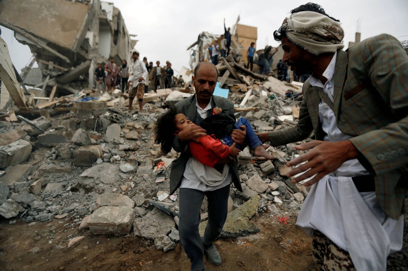 Un hombre socorre a una niña tras un bombardeo saudí en Saná, Yemen. (Reuters)