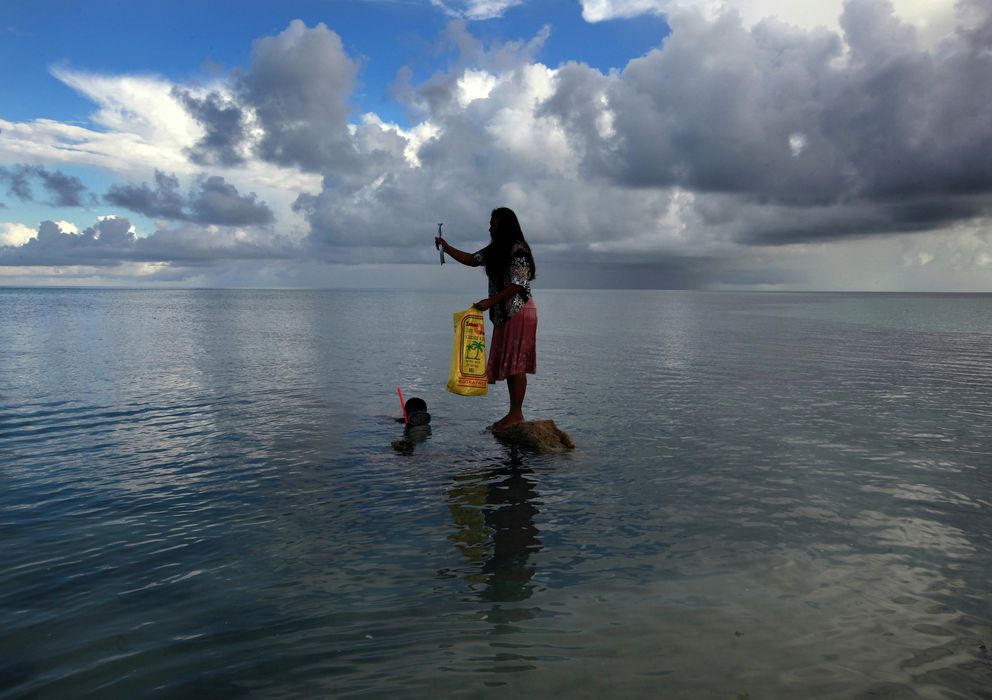 Foto: Una mujer, Binata Pinata, sobre un roca mientras su marido pesca en la pequeña isla-estado de Kiribati, en el centro del Pacífico (Reuters). 