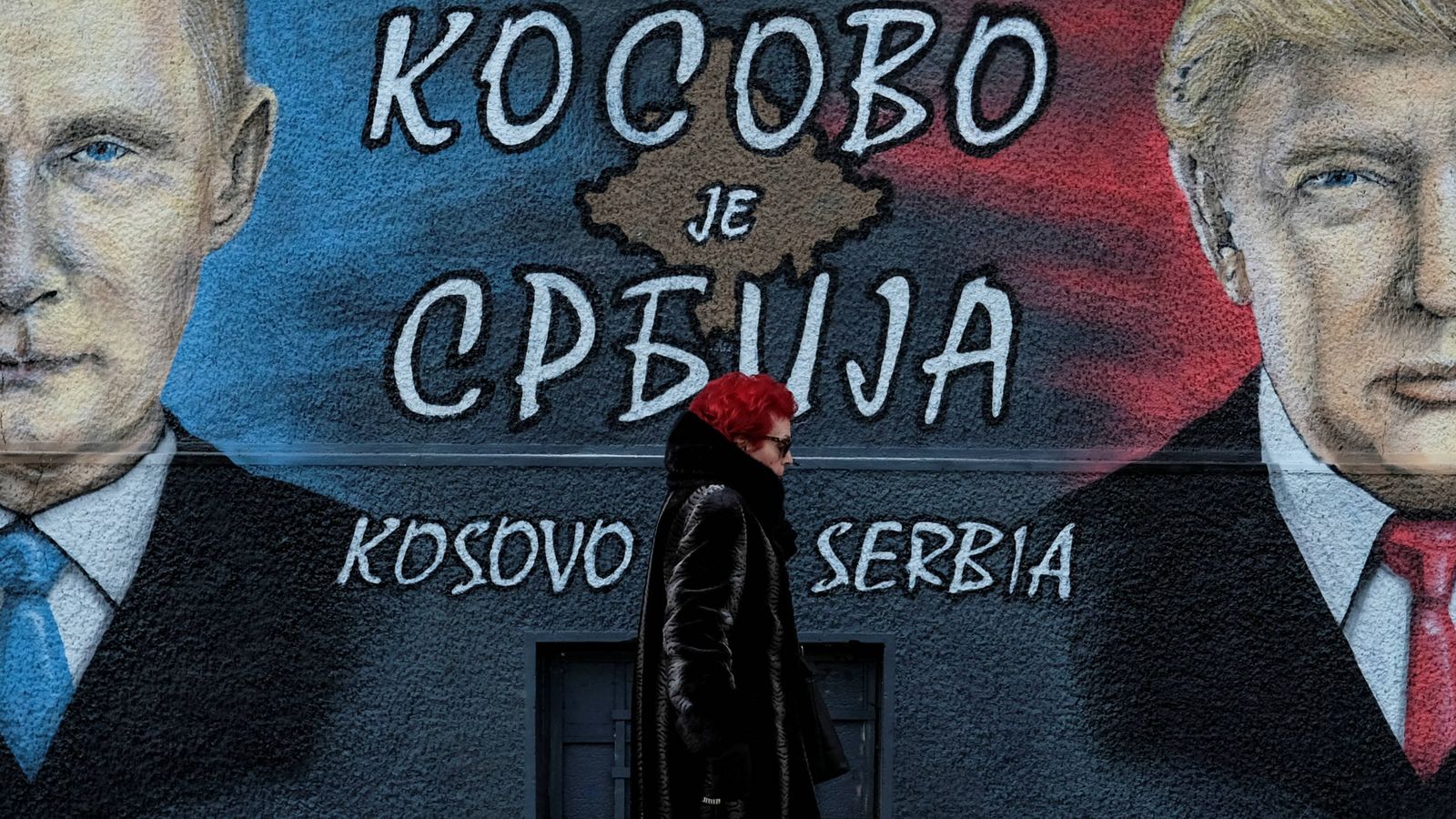 Foto: Una mujer pasa ante un mural con Trump y Putin en Belgrado. La pintada dice: "Kosovo es Serbia" (Reuters).