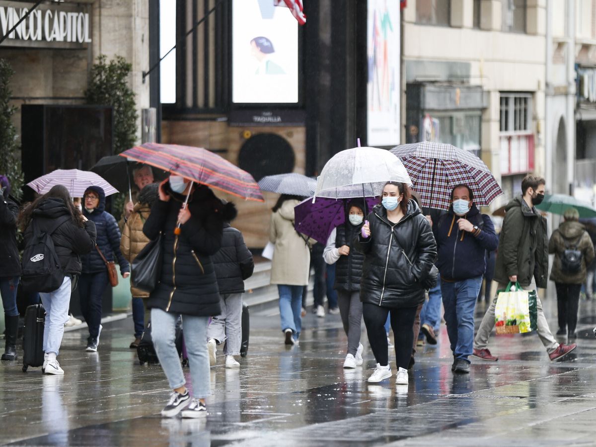 Foto: arias personas se protegen de la lluvia con paraguas en el centro de Madrid. (EFE)
