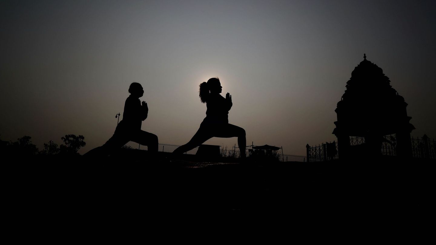 Dos personas hacen el saludo al sol en India | EFE  Jagadeesh Nv