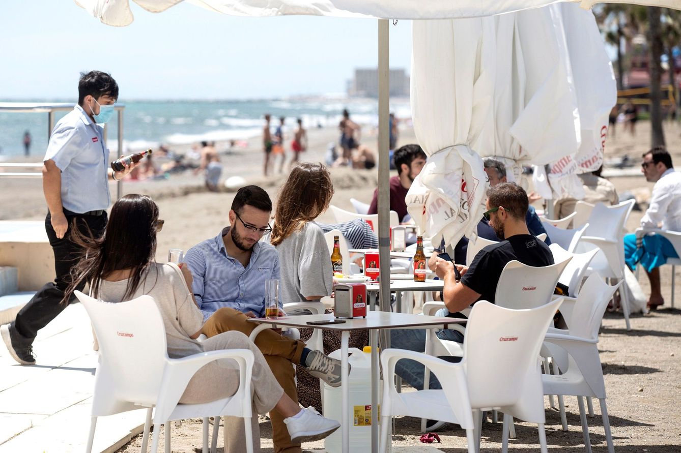 Varias personas disfrutan del buen tiempo en los chiringuitos de la playa de La Misericordia, de Málaga. (EFE/Daniel Pérez)